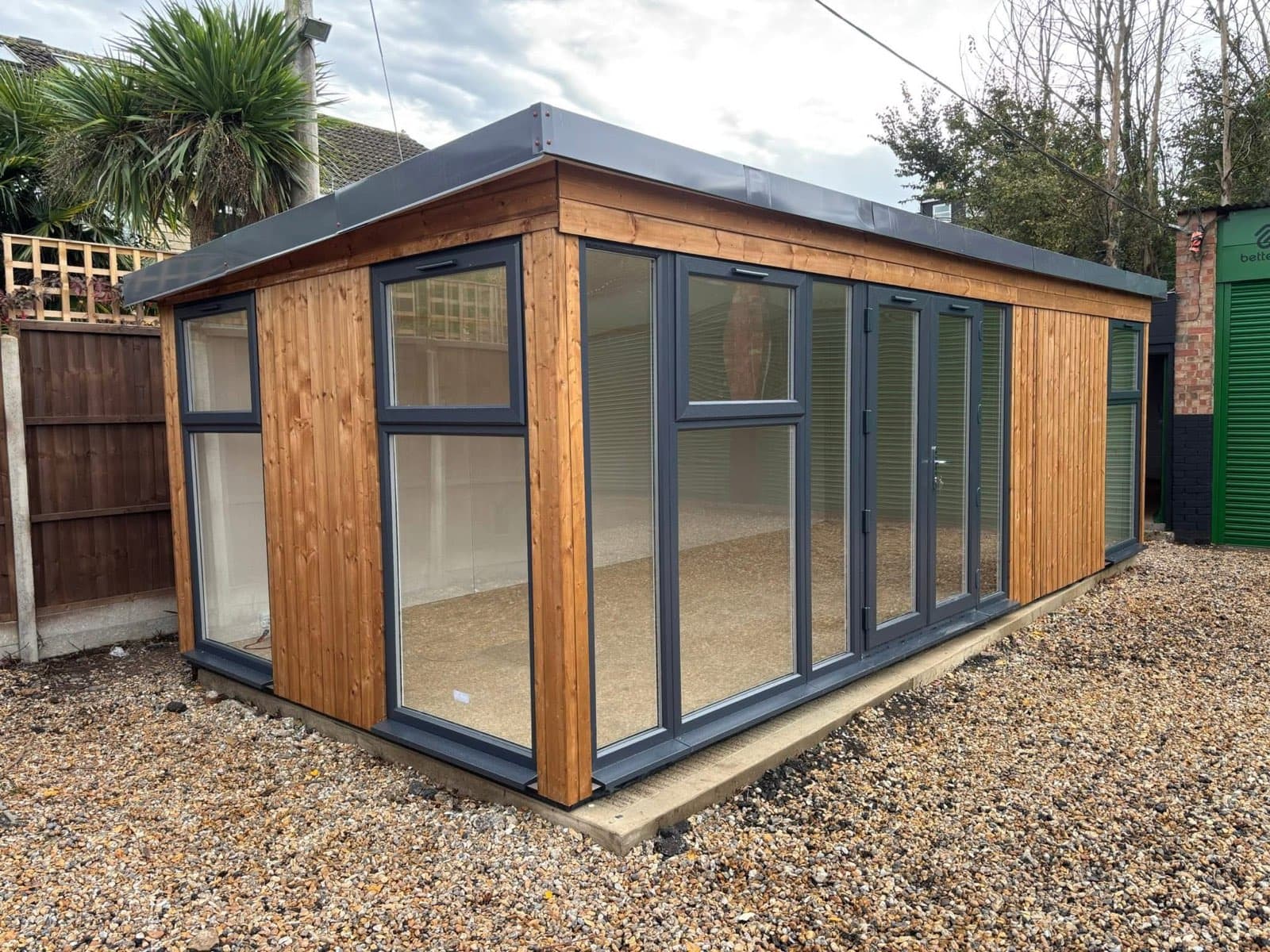 Timber-clad garden room with a fully glazed front in anthracite frames, on a shingle base with the interior still to be fitted out