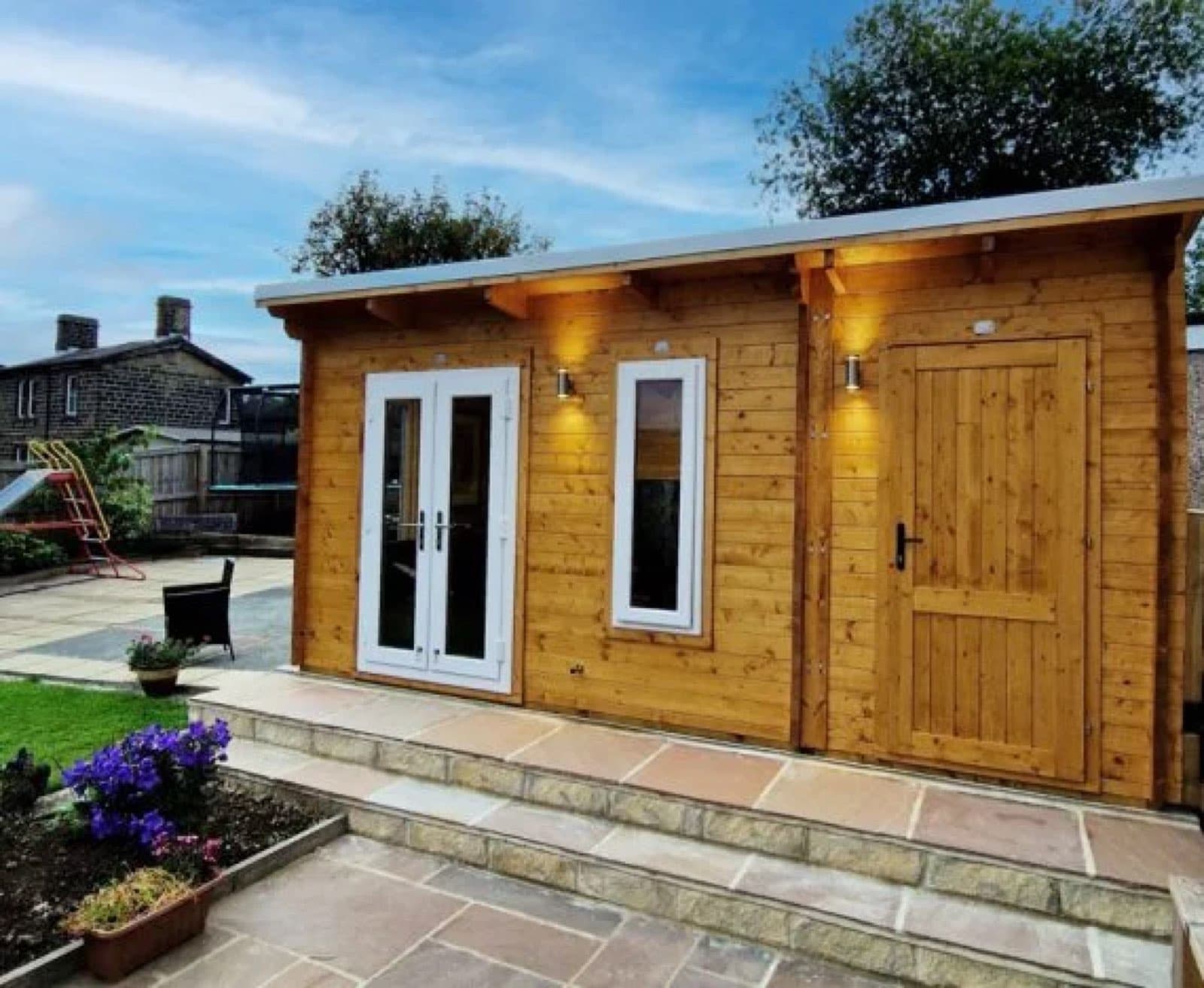 Honey log cabin with white French doors and a separate store door, approached by stone steps and a paved patio