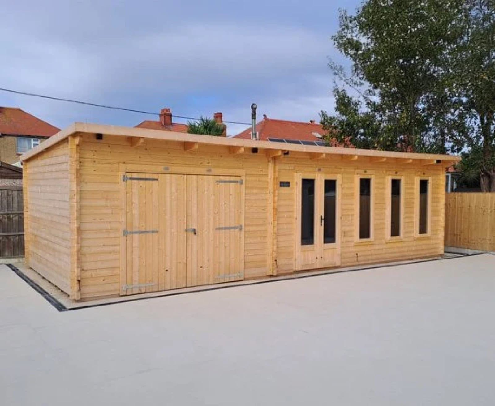 Large untreated pent log cabin and garage with double timber doors and a glazed section, on a concrete base
