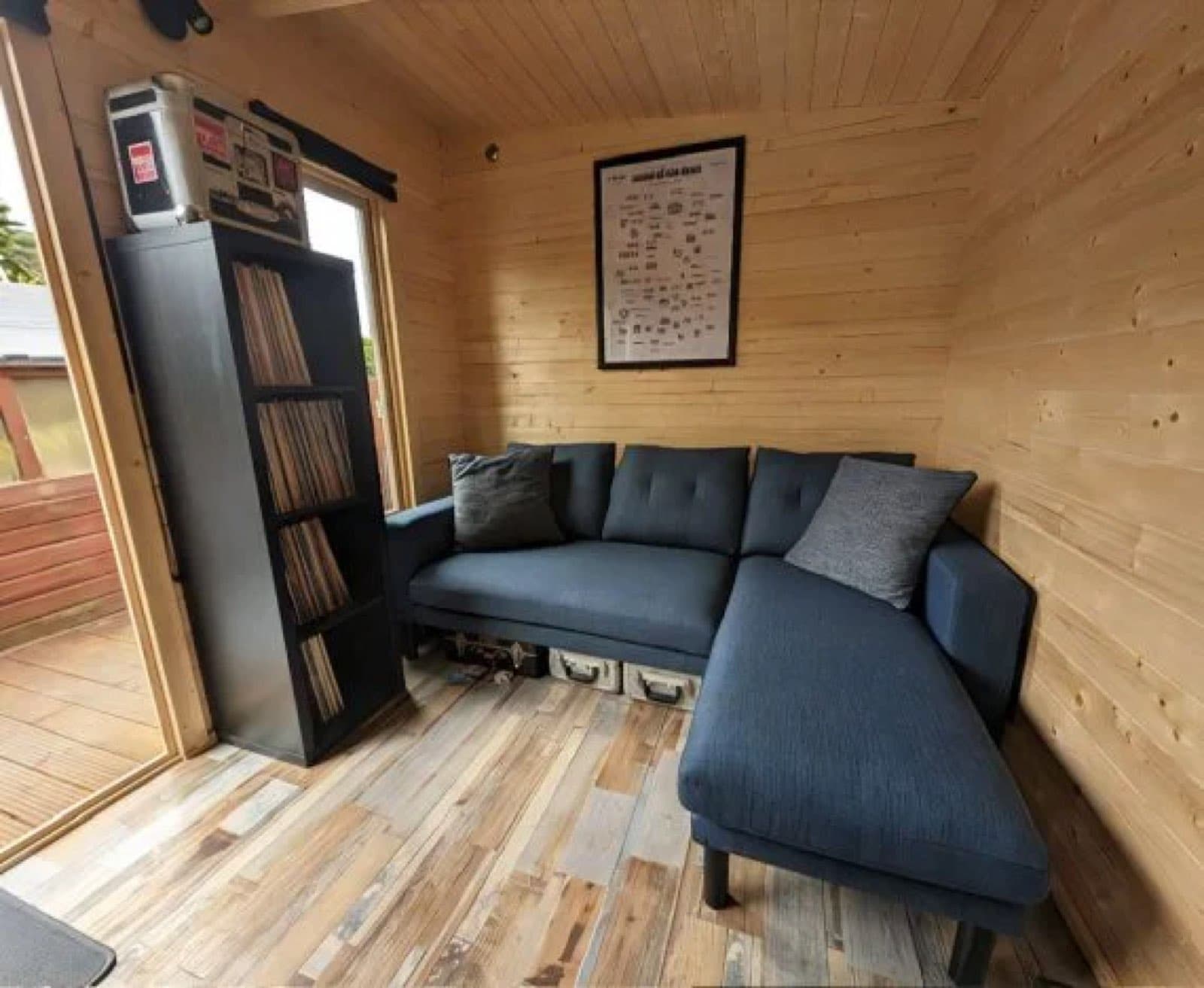 Inside a log cabin snug with a blue corner sofa, record shelving and a wooden floor