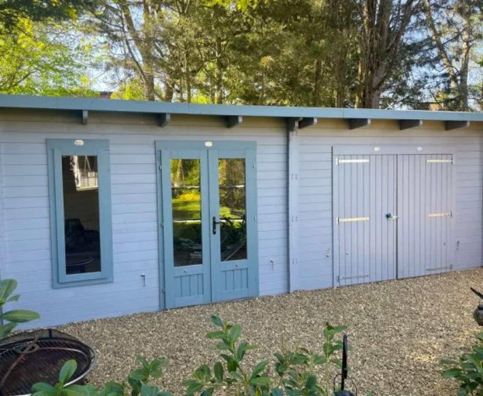 White and duck-egg painted pent cabin with glazed French doors and double store doors, on a gravel base